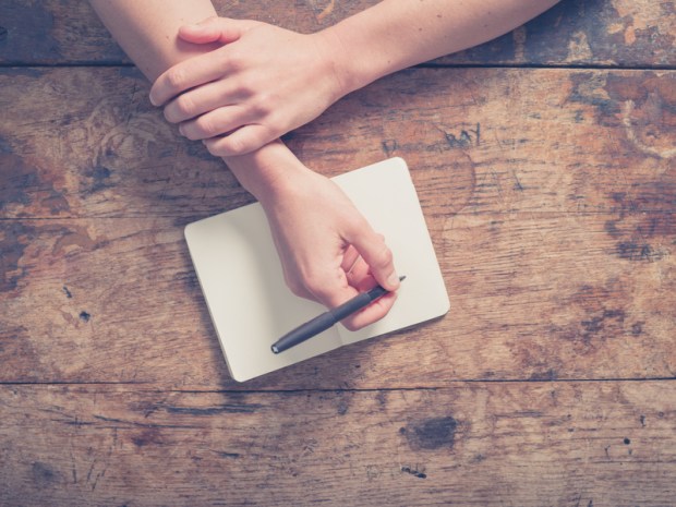 Woman writing in notepad at wooden table