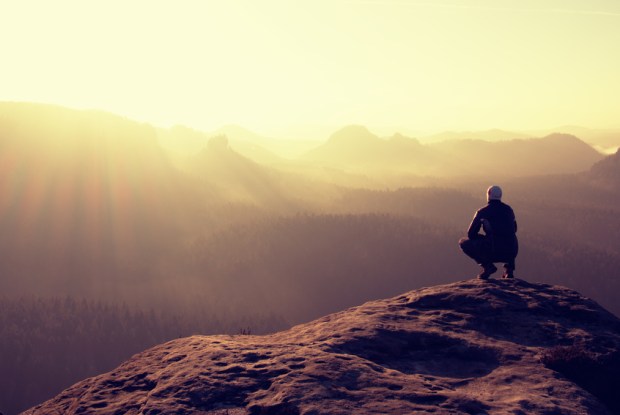 Slim tourist on peak of rock in autumn empires park