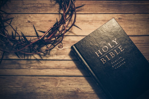Bible with a crown of thorns on a wooden table